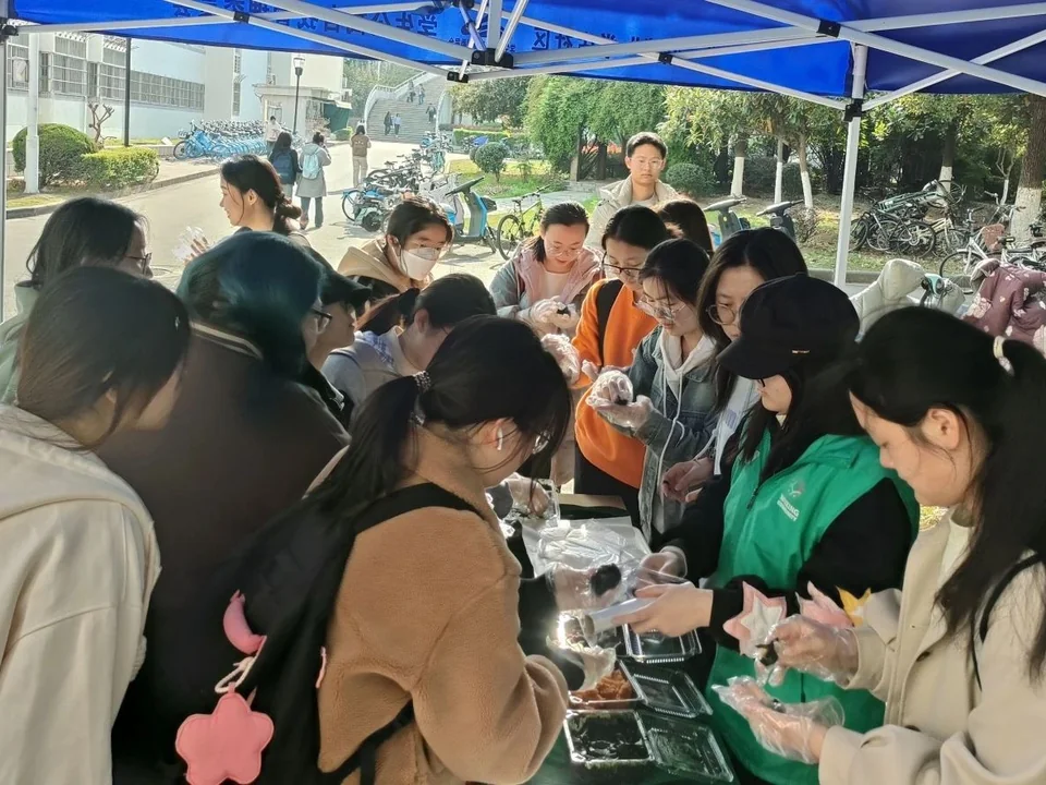 同学们在校园户外摊位参加青团制作活动